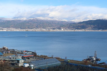 諏訪湖から見る山は雪で白くなっている